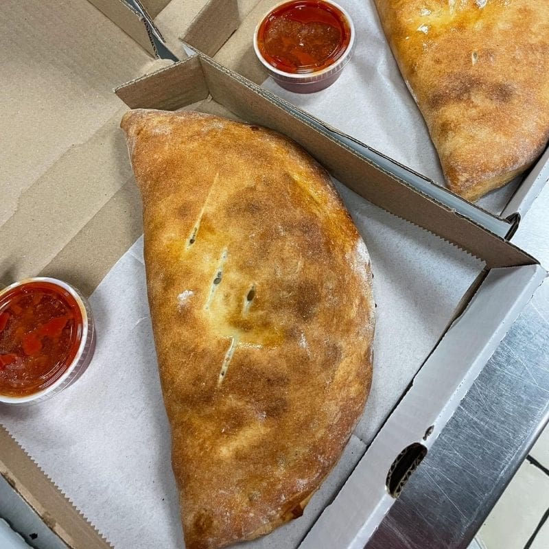 a Stromboli in a box with a side or marinara sauce