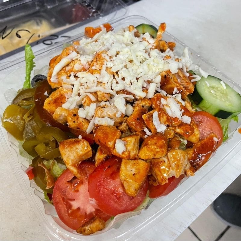 A buffalo chicken salad with tomatoes, cucumbers, peppers, and cheese