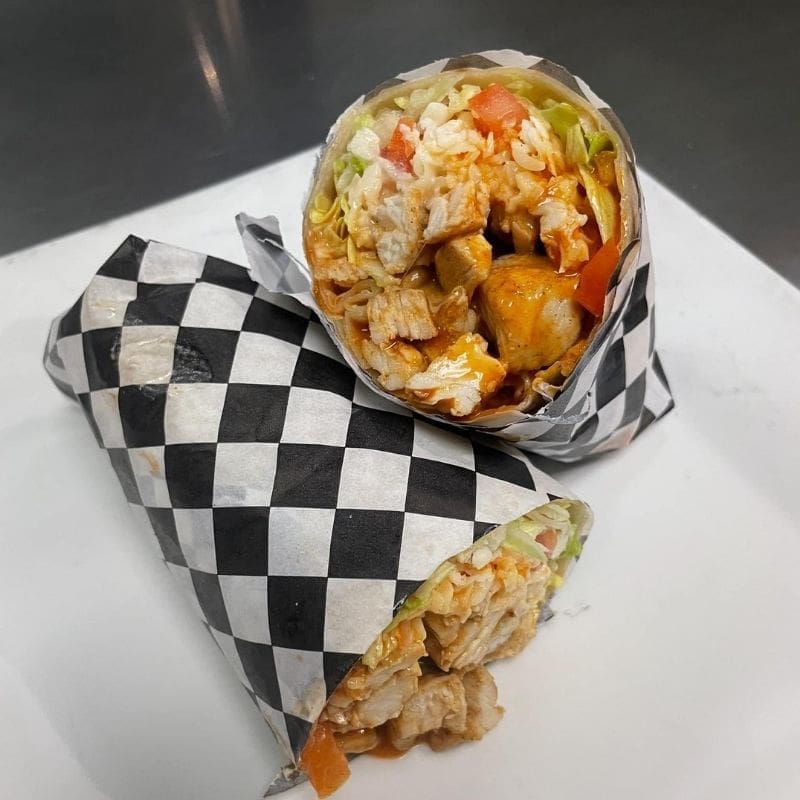 A buffalo chicken wrap on a white plate with a black and white checkered paper