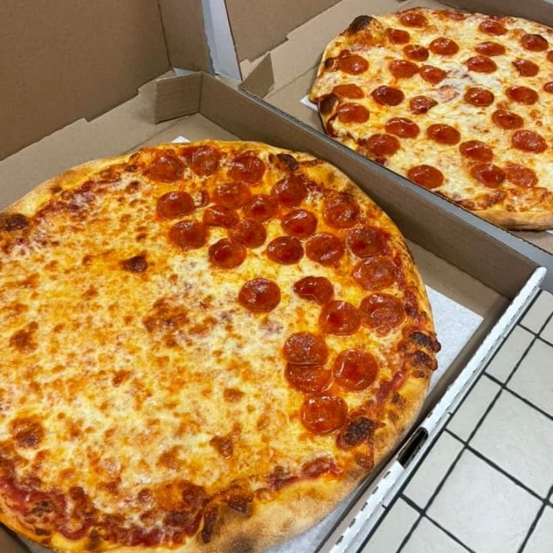 2 pizzas in boxes, one half cheese and half pepperoni and one whole pepperoni